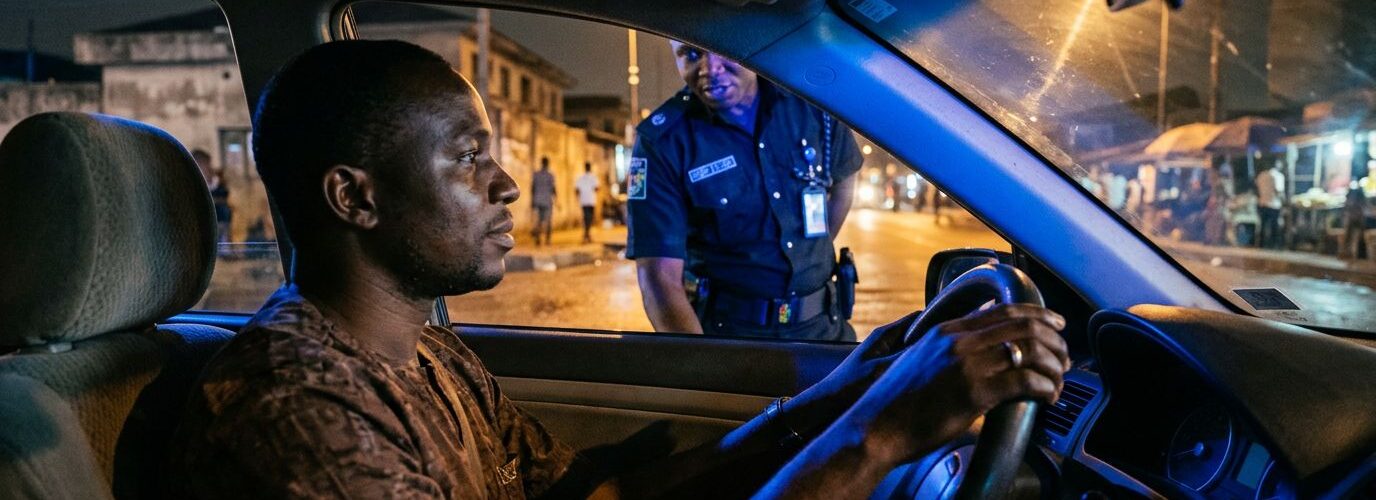 A calm driver keeps hands on the steering wheel during a nighttime traffic stop in Nigeria.