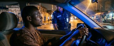 A calm driver keeps hands on the steering wheel during a nighttime traffic stop in Nigeria.