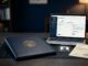 University transcript documents, a payment receipt, and laptop arranged on a dark desk.